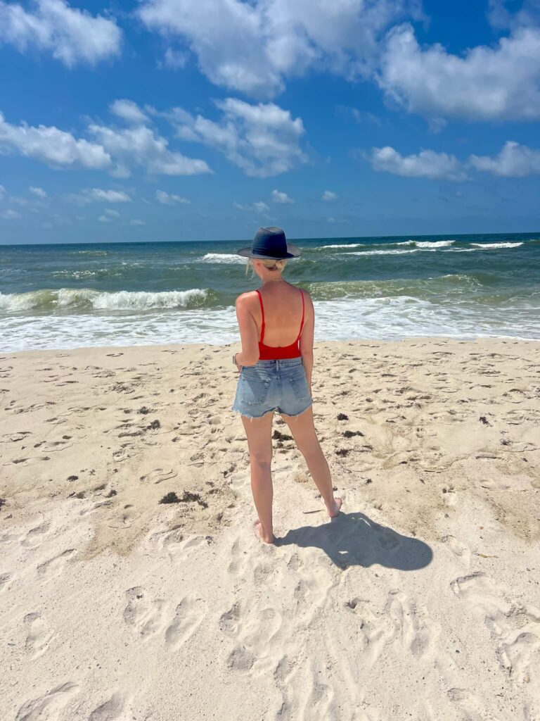 Essential Beach Packing List Red One Piece Swimsuit & Cutoffs what to wear to the beach beach style inspo Nashville personal stylists share the best swimwear the best beach accessories beach outfit how to style cutoffs on the beach how to wear cutoffs as a swim cover up